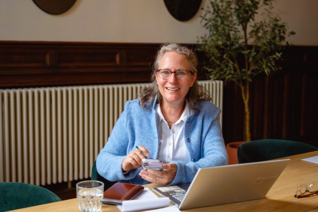 Judith van Twist, adviseur bij Eigenwijs Advies, achter haar laptop met telefoon in de hand